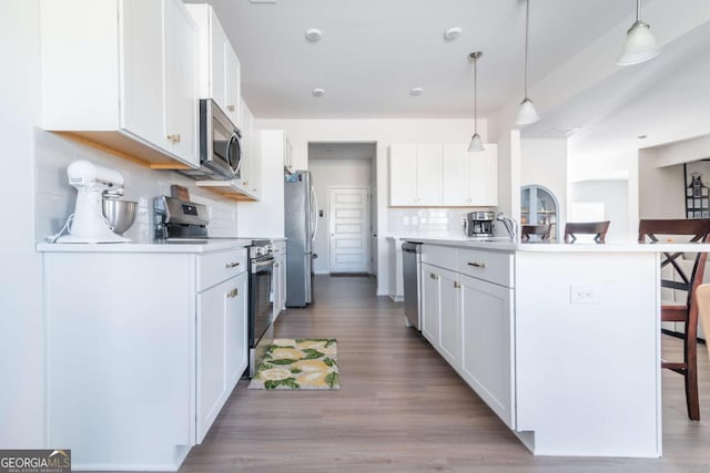 kitchen with white cabinetry, appliances with stainless steel finishes, backsplash, and a breakfast bar area