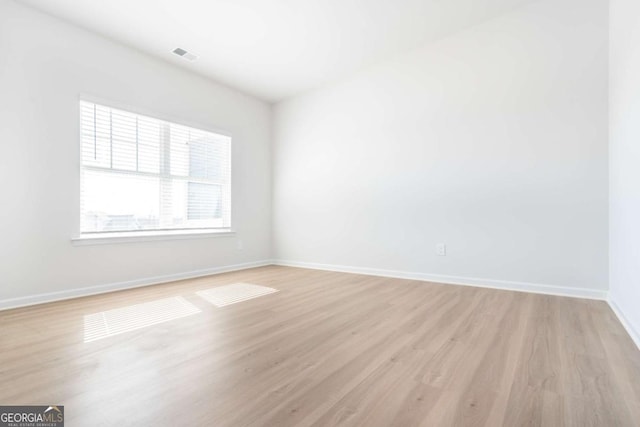 empty room featuring light wood-style flooring, visible vents, and baseboards