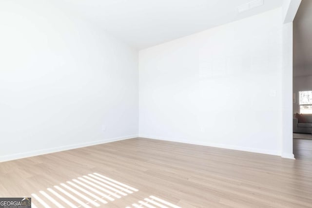 empty room with light wood-style flooring and baseboards