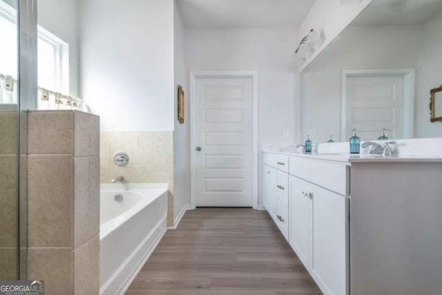 full bath with wood finished floors, a bath, and vanity