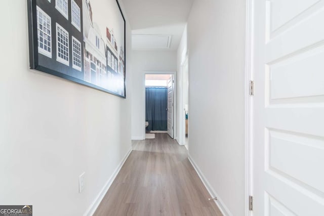 hall featuring wood finished floors, attic access, and baseboards