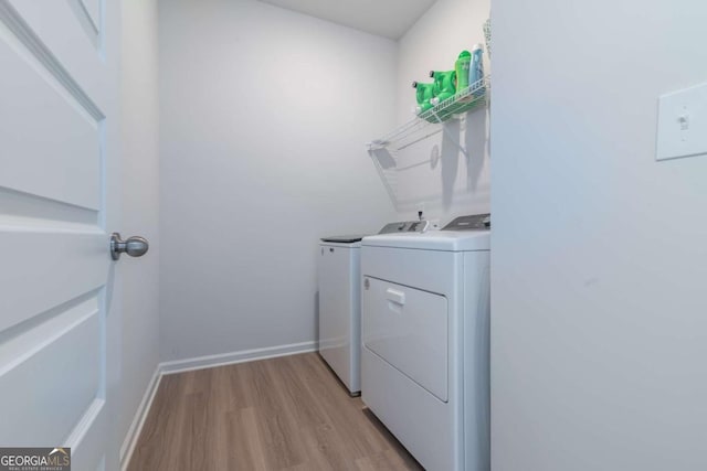 washroom featuring baseboards, laundry area, washing machine and clothes dryer, and light wood-style floors