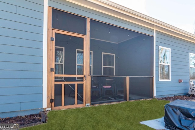 back of property with a sunroom and a lawn