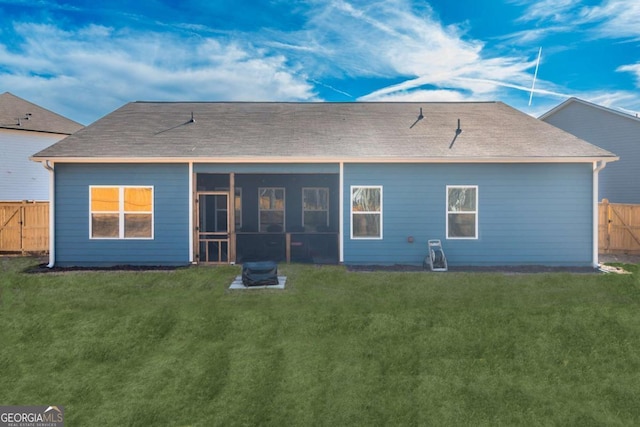 rear view of house with fence private yard, a sunroom, a gate, and a lawn