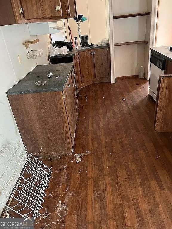 kitchen featuring dark wood-type flooring, dark countertops, brown cabinetry, and dishwasher