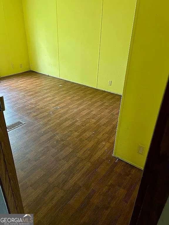 empty room featuring visible vents and dark wood finished floors