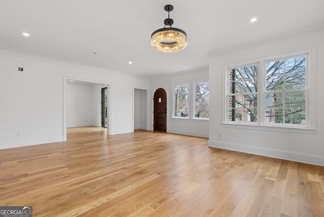 unfurnished living room with light wood-type flooring, baseboards, and ornamental molding