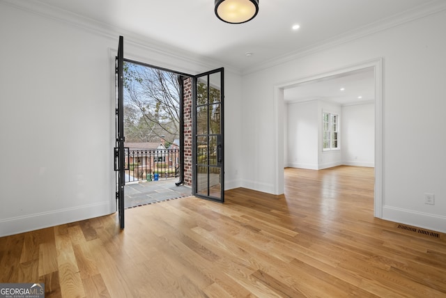 unfurnished room with light wood-style floors, plenty of natural light, visible vents, and crown molding