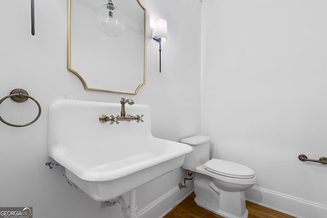 bathroom featuring a sink, wood finished floors, toilet, and baseboards