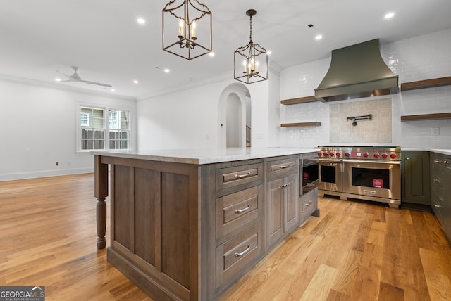 kitchen with wall chimney exhaust hood, double oven range, open shelves, and light countertops