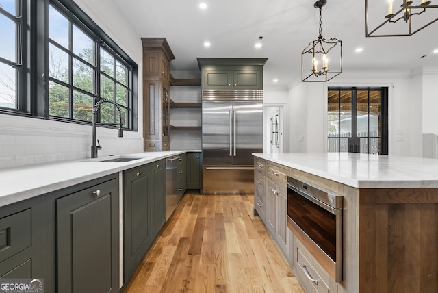 kitchen featuring light wood finished floors, decorative backsplash, appliances with stainless steel finishes, open shelves, and a sink