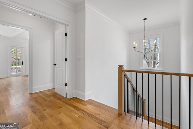 hallway featuring a chandelier, light wood finished floors, an upstairs landing, and crown molding