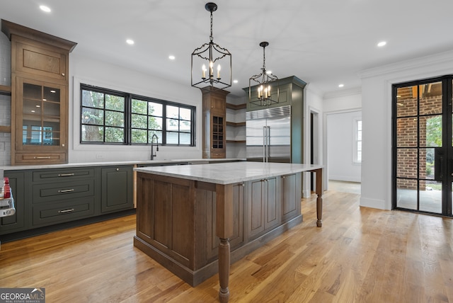 kitchen with built in fridge, a center island, light wood finished floors, open shelves, and a sink