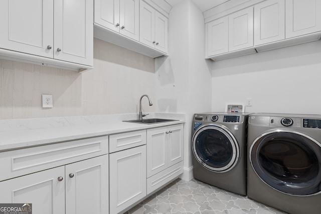 laundry room with cabinet space, washer and dryer, and a sink