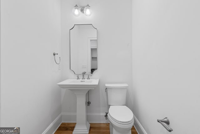 bathroom with wood finished floors, toilet, and baseboards