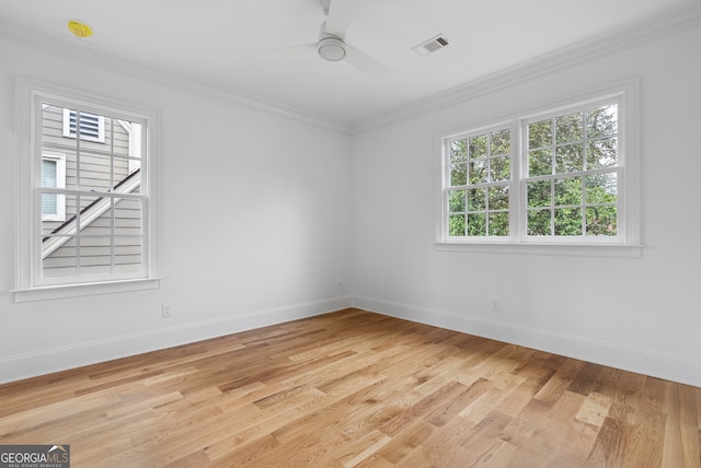 unfurnished room with light wood finished floors, baseboards, visible vents, and crown molding