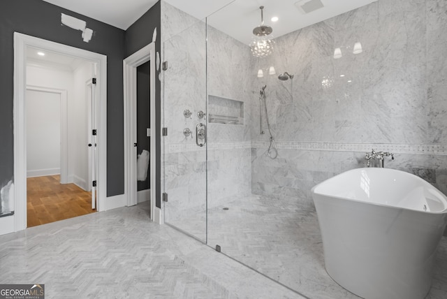 full bathroom with a freestanding bath, a marble finish shower, visible vents, and tile walls