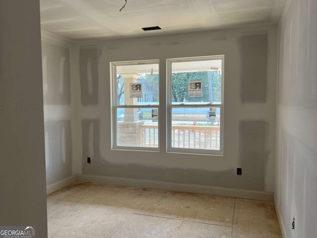 empty room featuring plenty of natural light, visible vents, and baseboards