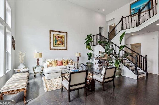 living room featuring stairway, a towering ceiling, and wood finished floors