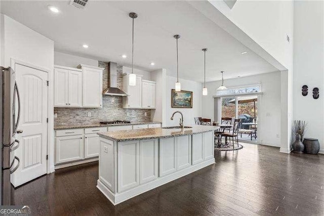 kitchen featuring stainless steel appliances, white cabinets, a sink, and wall chimney range hood