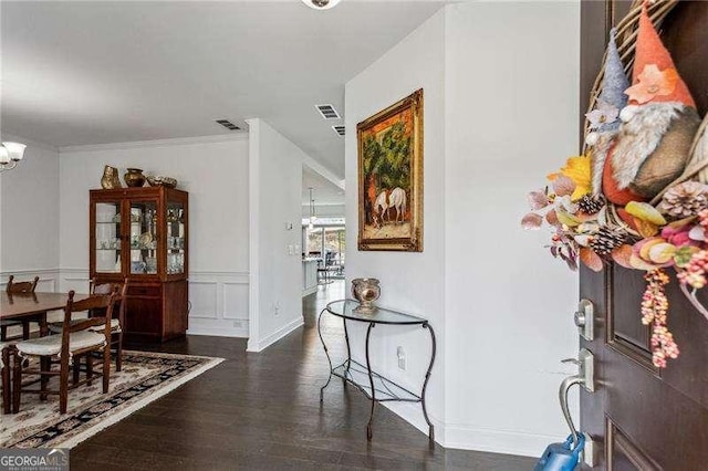 foyer featuring crown molding, visible vents, a notable chandelier, and wood finished floors