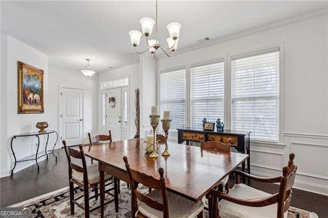 dining room featuring crown molding, a chandelier, a decorative wall, and wood finished floors