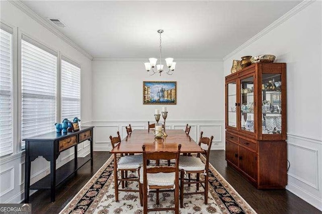 dining room with a chandelier, a decorative wall, and crown molding