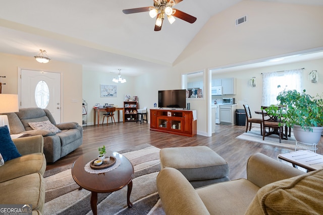 living room featuring visible vents, wood finished floors, high vaulted ceiling, baseboards, and ceiling fan with notable chandelier