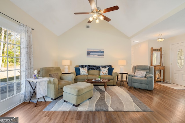 living area with high vaulted ceiling, wood finished floors, visible vents, and a ceiling fan