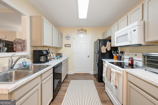 kitchen with white appliances, baseboards, wood finished floors, light countertops, and a sink