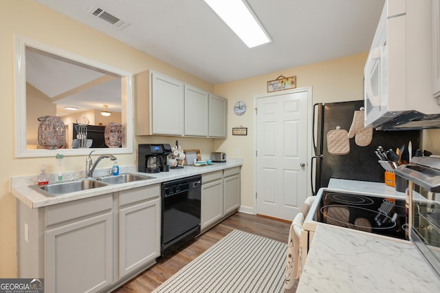 kitchen with light countertops, visible vents, a sink, wood finished floors, and white appliances