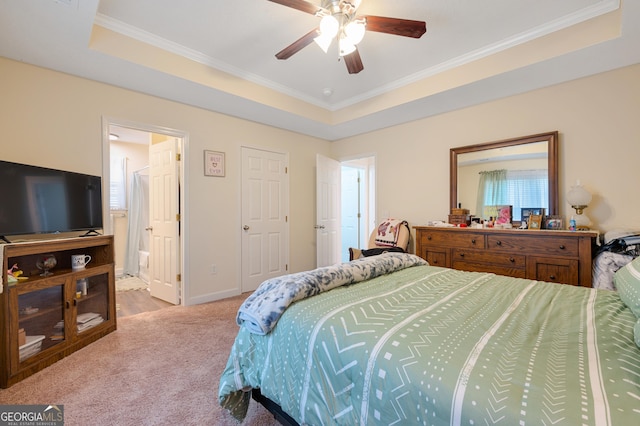 carpeted bedroom with ornamental molding, a tray ceiling, connected bathroom, and baseboards