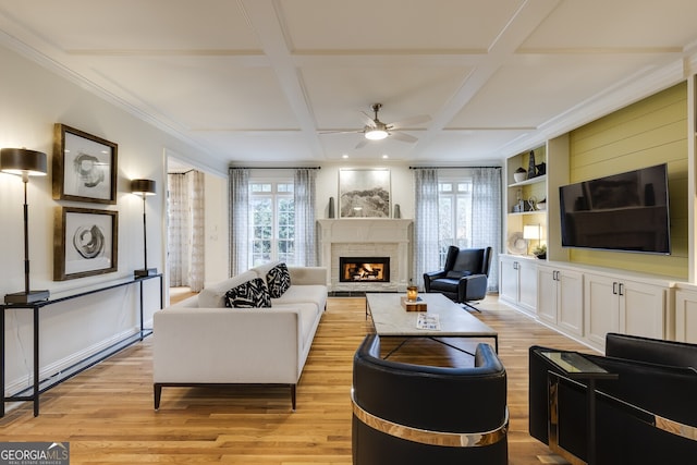 living area with coffered ceiling, light wood-style flooring, and a healthy amount of sunlight