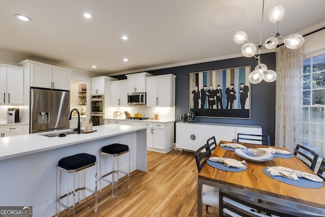 kitchen featuring a sink, light countertops, ornamental molding, appliances with stainless steel finishes, and backsplash