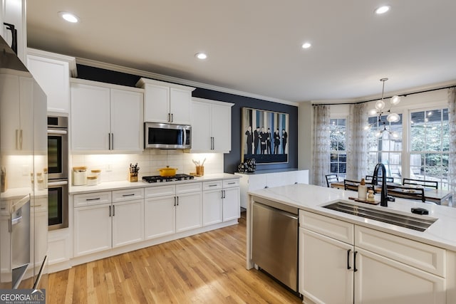 kitchen with appliances with stainless steel finishes, light countertops, a sink, and tasteful backsplash