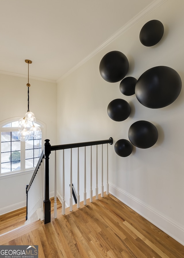 interior space featuring ornamental molding, an inviting chandelier, wood finished floors, and baseboards