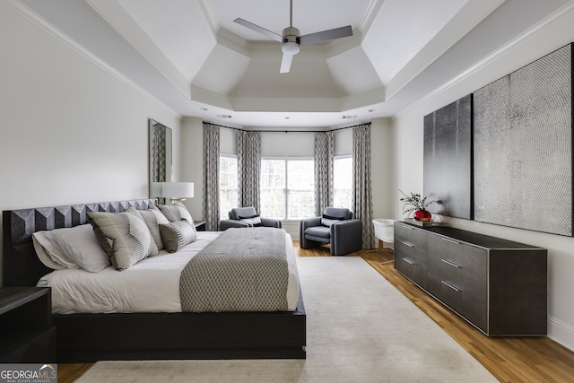 bedroom with ornamental molding, ceiling fan, wood finished floors, and a raised ceiling