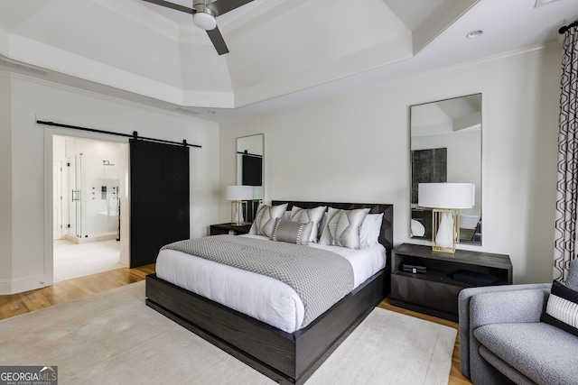 bedroom featuring a barn door, wood finished floors, and crown molding