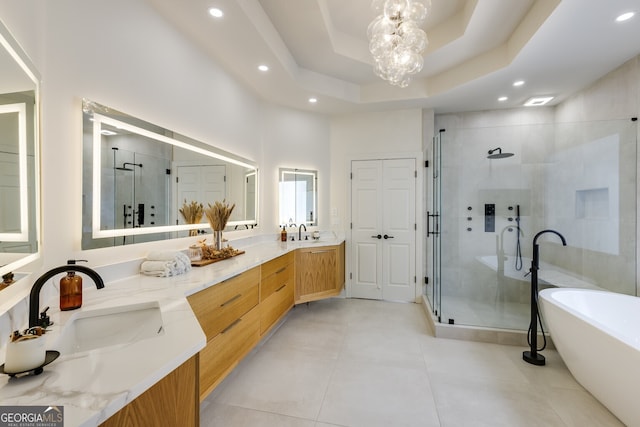 bathroom with double vanity, a stall shower, a freestanding bath, a chandelier, and a sink