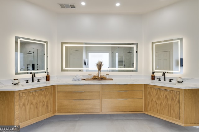 full bath featuring double vanity, a stall shower, visible vents, and a sink