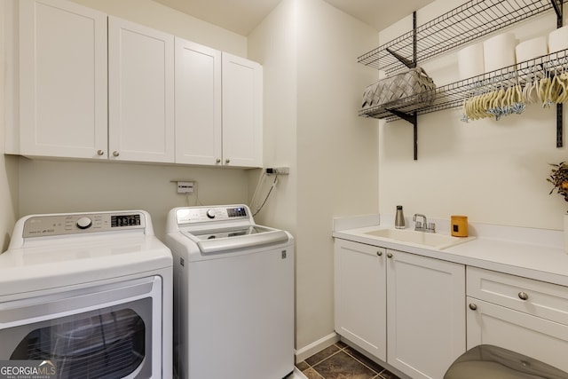 laundry room featuring a sink, dark tile patterned flooring, washing machine and clothes dryer, and cabinet space