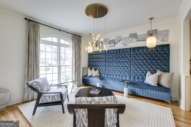 living area featuring baseboards, a chandelier, wood finished floors, and ornamental molding