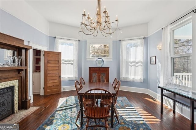 dining room with hardwood / wood-style floors, plenty of natural light, a chandelier, and a tiled fireplace