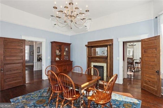 dining room featuring baseboards, a fireplace, an inviting chandelier, and wood finished floors