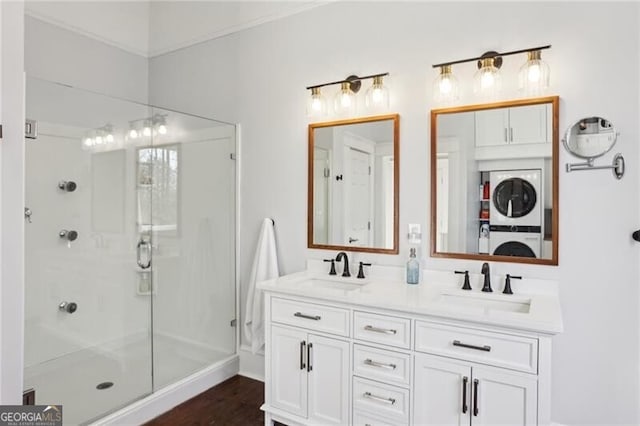 bathroom with a stall shower, a sink, and stacked washer and clothes dryer