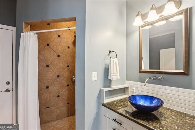 full bath featuring tiled shower, vanity, and tasteful backsplash