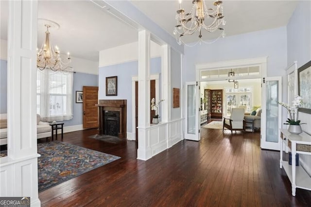 foyer entrance featuring wood-type flooring, a chandelier, french doors, and a fireplace with flush hearth