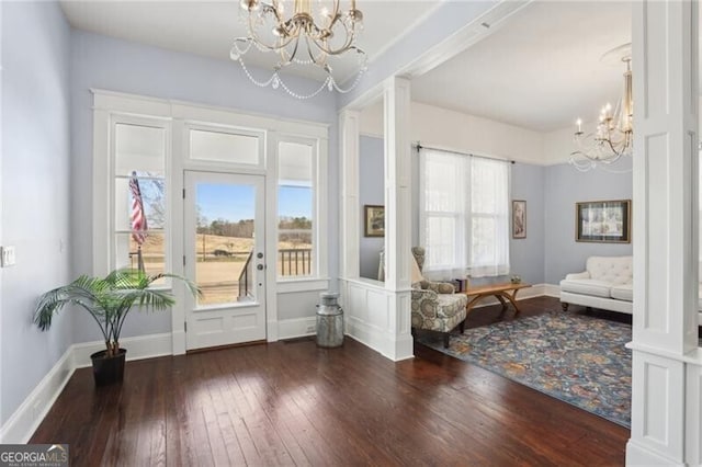 doorway featuring a chandelier, wood-type flooring, and baseboards