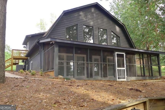 back of property featuring central air condition unit, a sunroom, and a gambrel roof