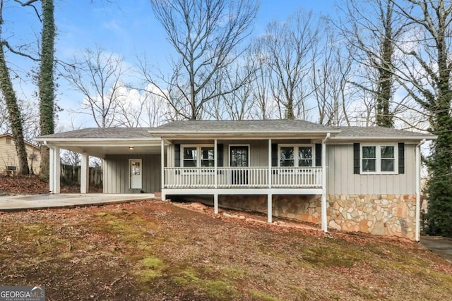 ranch-style house featuring stone siding, an attached carport, covered porch, and board and batten siding